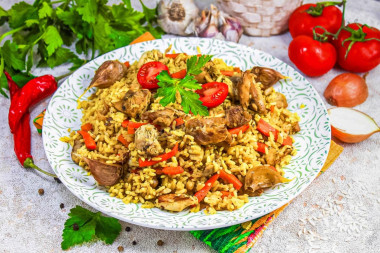 Рассыпчатый плов с курицей в кастрюле на плите Рассыпчатый плов с курицей в кастрюле на плите
