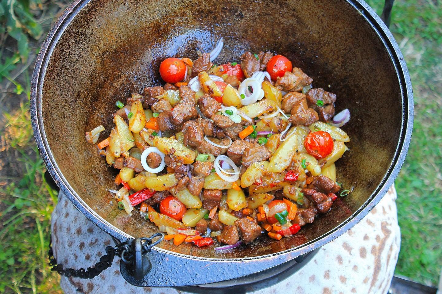 Блюда в казане на костре из свинины и картошки и овощей