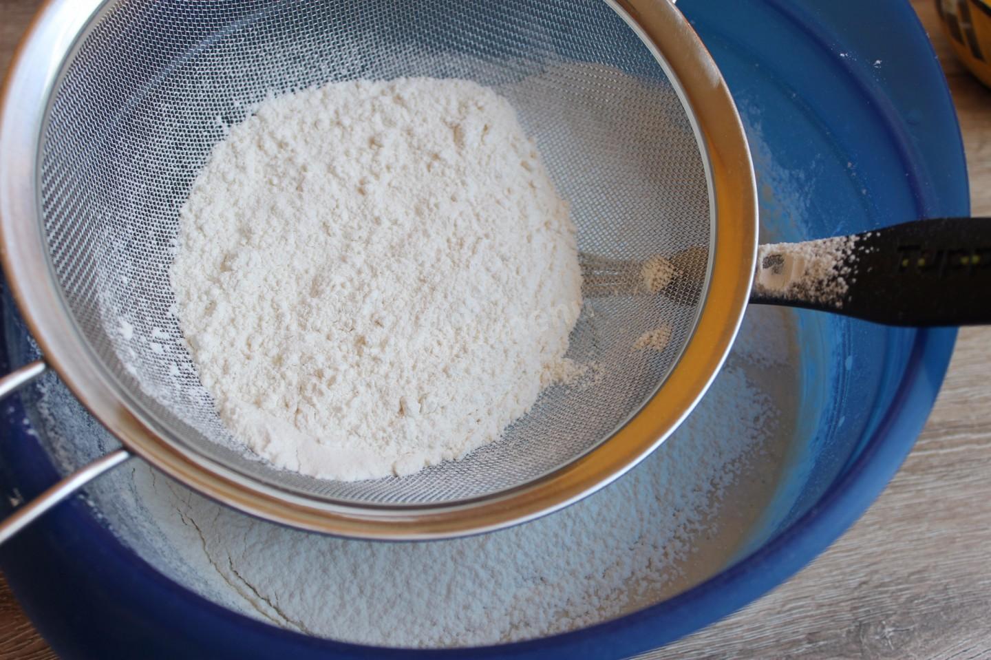 В дрожжевое тесто добавляют соду. Муку смешать с разрыхлителем и просеять. Всыпьте просеянную муку и соду, тщательно перемешайте.. Просеять муку во взбитые яйца. Мука в миске с сахаром.