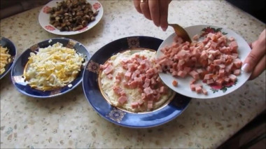 Рецепт - Слоеный салат Ромашка с ветчиной и грибами - Шаг 3 -  Первым слоем выкладываем половину картофеля смешанного с майонезом, и разравниваем его. Сверху на картофель выкладываем порезанную кубиками ветчину, этот слой слегка смазываем майонезом. Сверху на ветчину выкладываем потертые яйца, нанесем немного майонеза. Четвертым слоем выкладываем обжаренные грибы, этот слой майонезом не смазываем.
