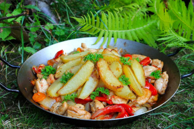 Курица с овощами в сковороде на костре