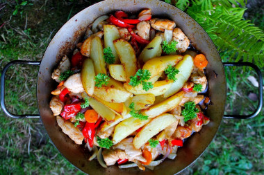 Курица с овощами в сковороде на костре