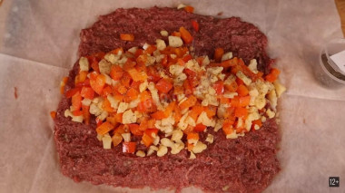 Рецепт - Мясной рулет с моцареллой и овощами - Шаг 2 -  2.Добавляем в фарш один зубчик чеснока, яйцо . Солим и перчим по вкусу. Замешиваем фарш до однородной массы , и формируем на пергаменте  основу для рулета толщиной не больше 1 см. Сверху посередине выкладываем цветную капусту и перец.