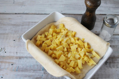 Рецепт - Пирог с картошкой рыбой на крахмальном тесте без дрожжей - Шаг 9 -  Мелким кубиком нарежьте очищенный и промытый картофель. Выложите его на тесто, поперчите, посолите.