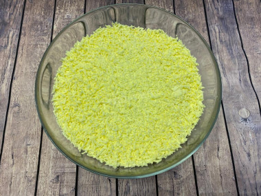 Рецепт - Мимоза с сыром легче легкого - Шаг 9 -  Поверх второго слоя, покрытого майонезом, натираем желтки. Вот тут как раз принципиально, чтобы терка была мелкая. Она создает эффект пушистости. Ну прям как веточка мимозы. Далее салат можно украсить по своему усмотрению. Например красиво выложить цифру 8 к празднику, или украсить зеленью.Приятного аппетита и легких экспериментов.