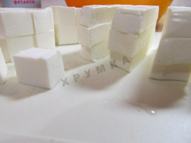 Рецепт - Салат маслины фетакса помидоры огурцы лук перец - Шаг 8 -  Что представляет собой фетакса? Фетакса – сырный продукт. Готовится из коровьего молока. Имеет более нейтральный вкус и запах, чем фета. По вкусу он напоминает брынзу. По текстуре похож на мягкий сливочный сыр. Нарежьте фетаксу кубиками среднего размера. Чтобы его было легче нарезать, положите упаковку на 15-20 минут в морозилку. Подмороженный сыр не будет так сильно прилипать к лезвию ножа.