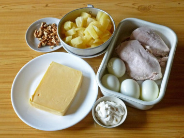 Рецепт - Сырный салат с грудкой, яйцами, ананасом и орехами - Шаг 3 -  Консервированные ананасы или кабачки откинуть на дуршлаг и дать стечь излишкам сиропа. Сваренную куриную грудку переложить из бульона на тарелку, чтобы остыла. Вареные яйца очистить от скорлупы. На 8 порций салата возьмем куриную грудку весом 500 г, 4 яйца, 200 г твердого сыра, 300 г консервированных ананасов (или в более экономном варианте – маринованных кабачков), пакетик майонеза и ядра пяти грецких орехов.