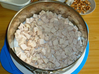 Рецепт - Сырный салат с грудкой, яйцами, ананасом и орехами - Шаг 6 -  Первым слоем на блюдо кладем кубики куриной грудки и распределяем их ровно.