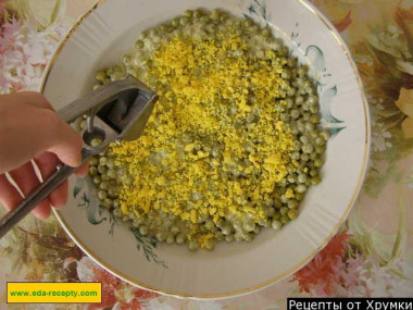 Рецепт - Салат куриное филе, соленые огурцы и майонез - Шаг 8 -  Посыпаем горошек желтком, сверху наносим майонез и посыпаем измельченным через пресс чесноком.