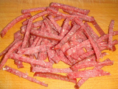 Рецепт - Салат с копченой колбасой, сыром, помидорами, яйцами - Шаг 2 -  С колбасы снимите кожицу. Нарежьте её тонкой соломкой, используя острый нож.