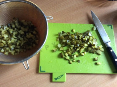 Рецепт - Оливье Lite-версия салат - Шаг 2 -  В самом начале режим соленые огурцы, размером с горошину. Лучше всего это сделать на первом этапе, чтоб потом не ждать. Откидываем на дуршлаг, подставляем тарелку или миску. В этом случае вся жидкость стечёт, и ваш салат не будет на следующий день как &quot