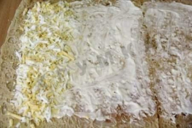 Рецепт - Лавашный рулет с сыром и печенью трески - Шаг 1 - Лист лаваша смазываем майонезом. Края лаваша лучше оставить чистыми, так будет удобнее заворачивать рулет и он будет более аккуратным. Яйца варим, чистим , натираем на крупной тёрке, выкладываем на лаваш , сформовав плотную полоску.