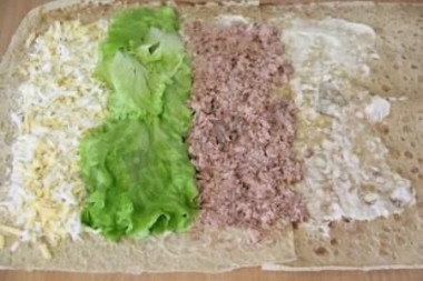 Рецепт - Лавашный рулет с сыром и печенью трески - Шаг 3 -  С печени трески сливаем лишнее масло, разминаем печень вилкой, выкладываем на лаваш рядом с листьями салата.