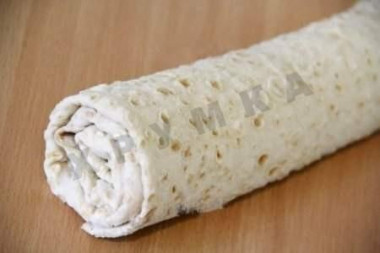 Рецепт - Лавашный рулет с сыром и печенью трески - Шаг 5 -  Заворачиваем пустые края лаваша на начинку, а затем сворачиваем лаваш в плотный рулет. Рулет заворачиваем в пищевую плёнку и убираем в холодильник на 2 часа.