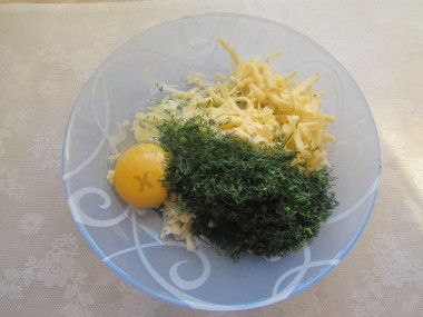 Рецепт - Запеканка из картошки с сыром и чесноком - Шаг 3 -  Делим сырную стружку на две равные части и перекладываем их в разные емкости. Одну половину сыра соединяем с яйцом и укропом, который нужно заранее помыть и измельчить ножом. Этой смесью покроем запеканку.