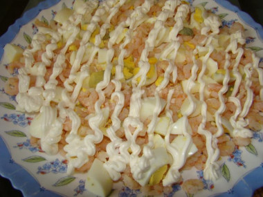 Рецепт - Салат с кальмарами, кукурузой, яйцами и креветками - Шаг 9 -  Теперь, когда подготовительная работа окончена, посмотрим, как сделать салат с креветками и кальмарами и кукурузой? Итак, приступаем к сборке салата. Первым слоем выкладываем креветки с яйцами. Смазываем слой майонезом. Я делала майонезную сеточку.