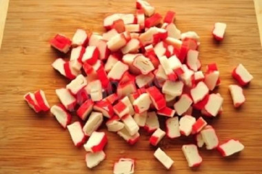 Рецепт - Салат Звёздочка на 23 Февраля из крабовых палочек - Шаг 1 - Крабовые палочки разделить пополам: одну часть нарезать мелкими кубиками и сложить в салатницу, а вторую часть нарезать ломтиками с косым сечением и отложить для украшения.