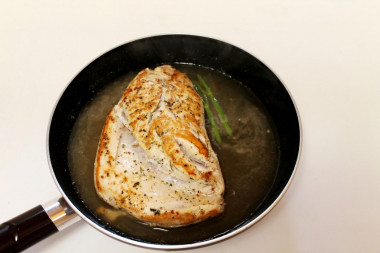 Рецепт - Грудки индейки на сковороде - Шаг 6 -  Теперь добавьте на сковороду горячую воду из чайника, вскипятив его предварительно к этому моменту. Положите в воду - будущий бульон - стебли зелени, кусок луковицы, сельдерея и тушите под крышкой после закипания на медленном огне около получаса, в середине варки на всякий случай переверните грудку.