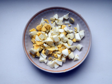 Рецепт - Салат крабовые палочки рис яйца - Шаг 4 -  Одновременно нужно поставить варить куриные яйца. Варим куриные яйца около 10 минут с момента закипания воды, воду лучше подсолить, чтобы скорлупа не лопнула, а после варки это упростит процесс чистки яиц. Дольше варить куриные яйца не нужно, иначе желток станет некрасивого синеватого цвета, если варить меньше – желток будет жидким. После варки воду сливаем, куриные яйца заливаем холодной водой, даем им остыть, чистим и нарезаем маленькими кубиками ножом.